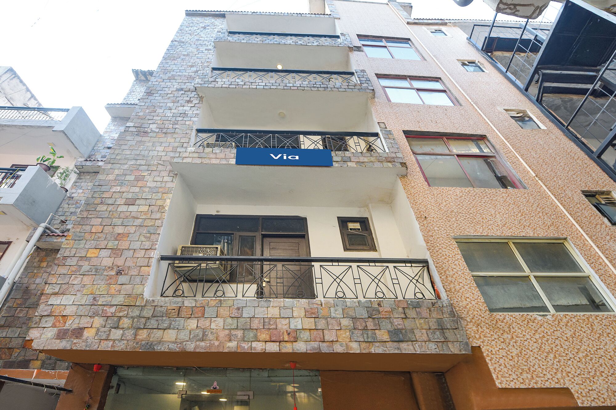 A multi-story building with a 'Via' sign, balconies, and a mix of brick and stone facades.