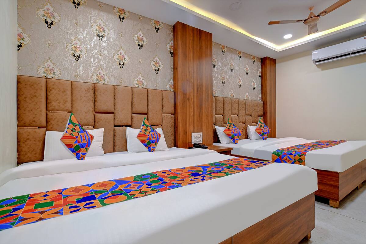 A hotel room with two beds, a wooden headboard, patterned wallpaper, and a ceiling fan.