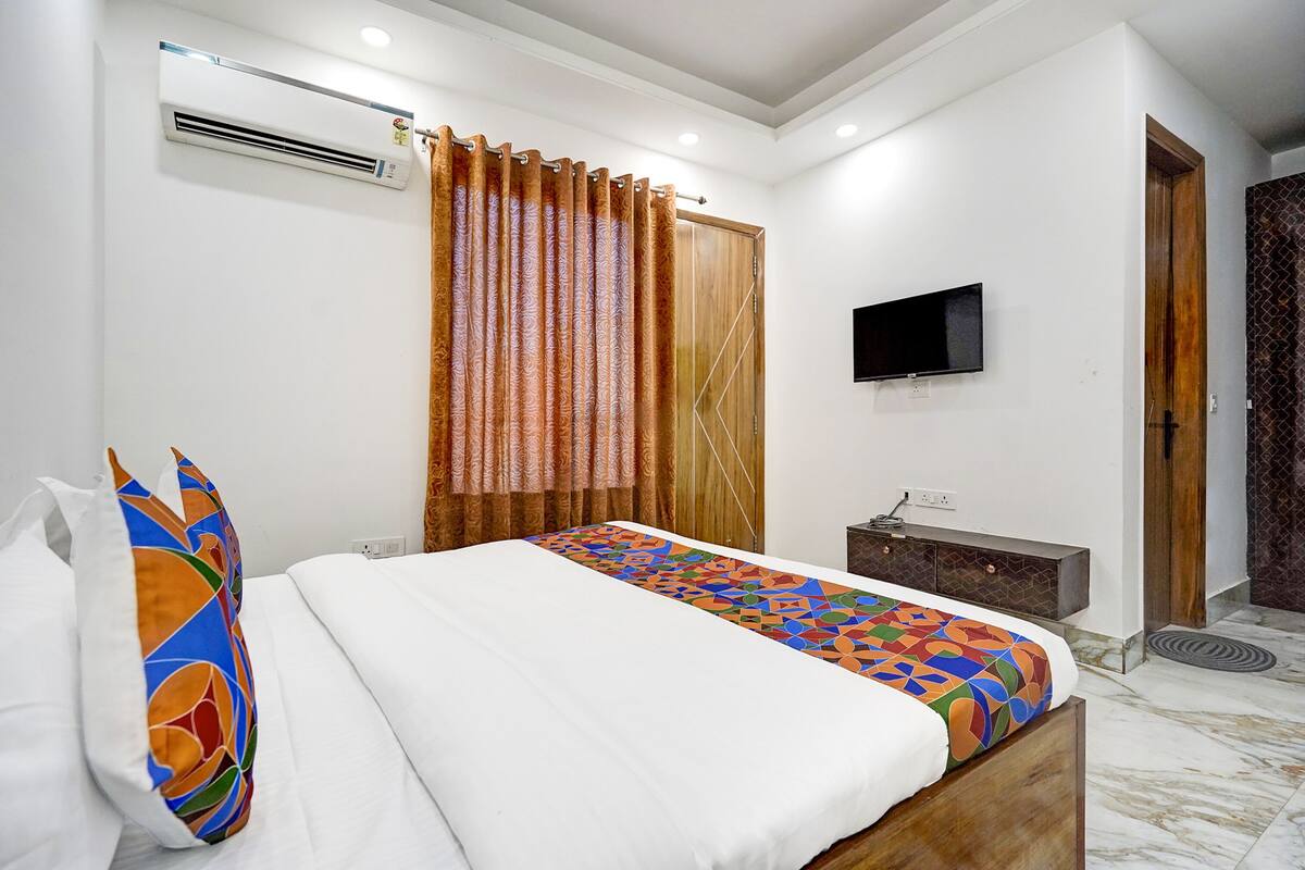 A bedroom with a bed, a TV, a wardrobe, and an air conditioning unit.
