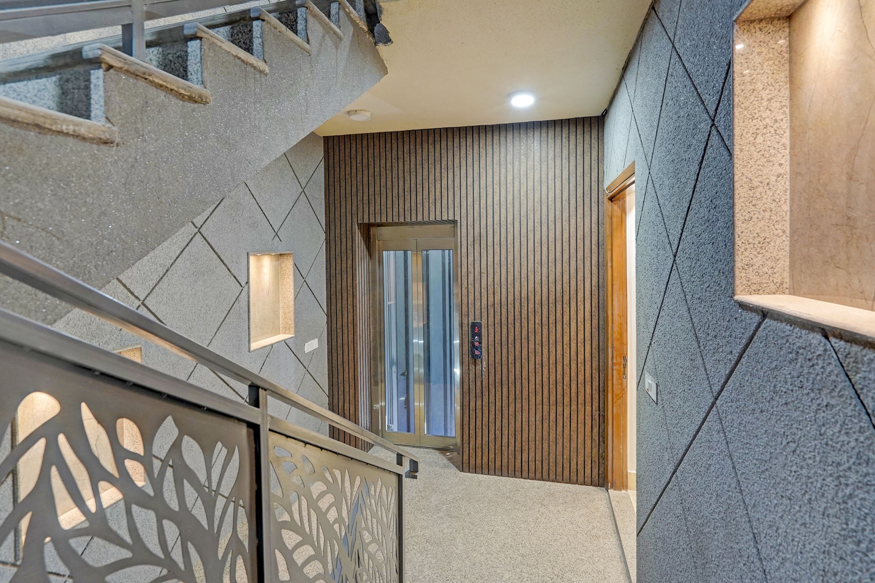 A modern interior with a staircase, a wooden panel wall, and a door with a glass panel.