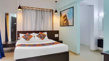 A hotel room with a large bed, a nightstand, a mirror, and a painting on the wall.