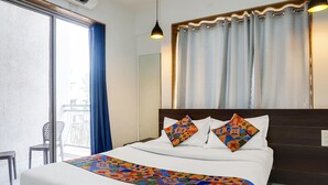 Ett hotellrum med en stor säng, utsikt över balkongen och ett fönster med gardiner.