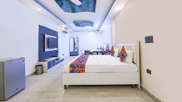 A modern hotel room with a bed, a desk, a TV, and a minibar. - Fabhotel Capital Inn (Greater Noida)