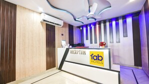 A reception desk with a modern design, a ceiling fan, and a sign for 'fab hotels'. - Fabhotel Capital Inn (Greater Noida)