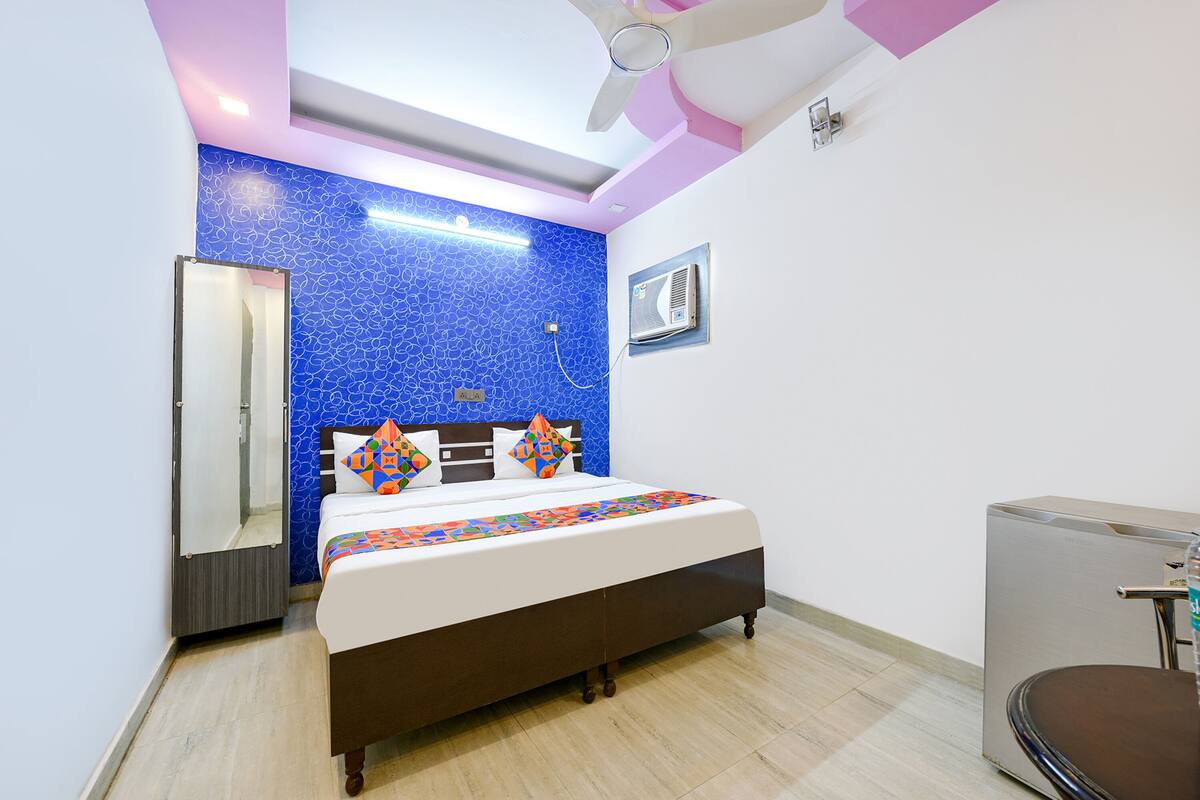 A bedroom with a bed, a wardrobe, a ceiling fan, and a wall-mounted air conditioner.