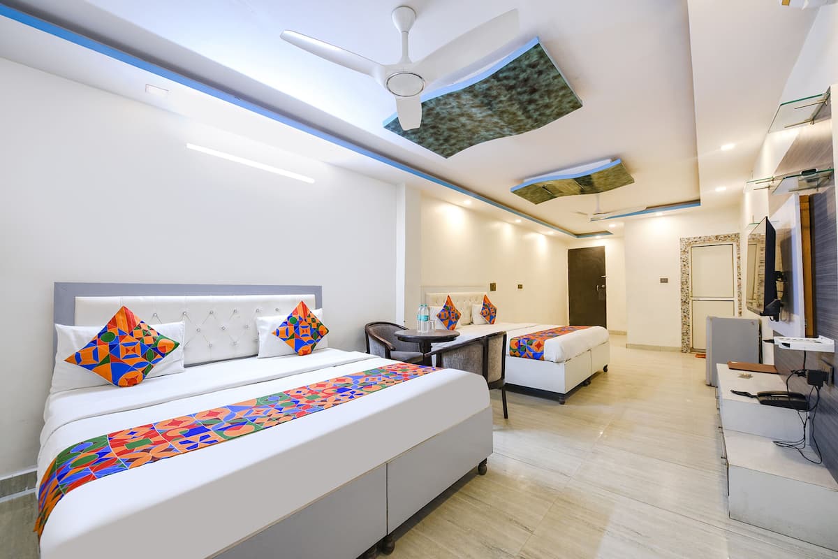A modern hotel room with a large bed, a desk, a chair, and a television.