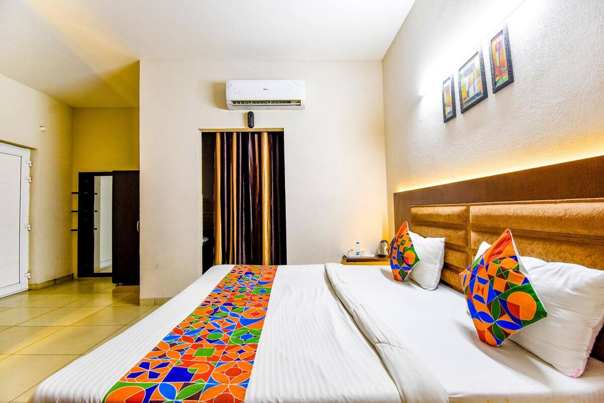 Une chambre d’hôtel avec un lit, une table de chevet, un appareil de climatisation et une porte.