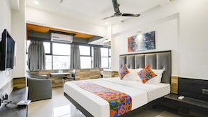 A modern hotel room with a large bed, a desk, a chair, and a TV. - FabHotel Prestige Elite (Nashik)
