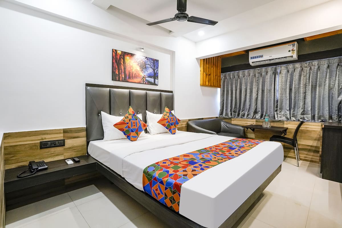 Quarto de hotel moderno com uma cama grande, uma escrivaninha e um ventilador de teto.