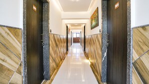 A hotel hallway with a polished floor, dark wood doors, and a modern light fixture. - FabHotel Prestige Elite (Nashik)