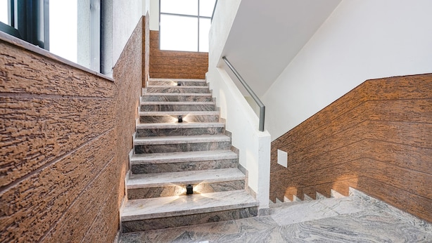 A modern staircase with marble steps and wooden paneling, leading to a bright interior space. - FabHotel Prestige Elite (Nashik)