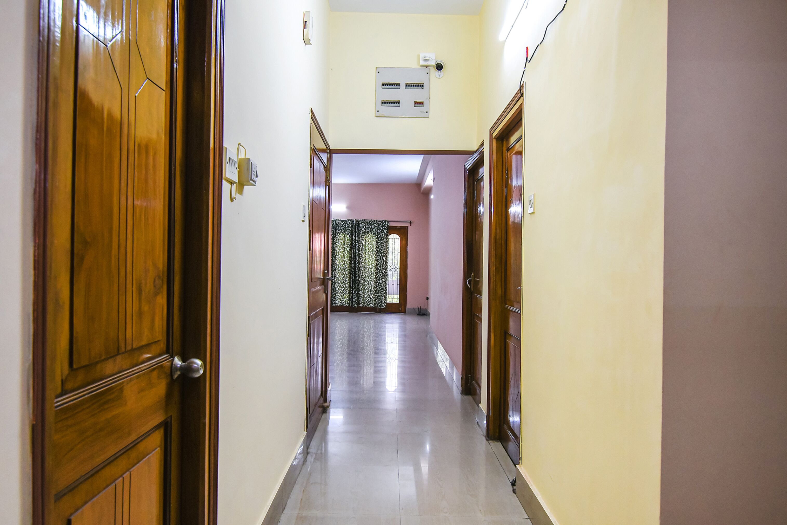 Un pasillo con puertas de madera, un interruptor de luz y un enchufe en la pared.