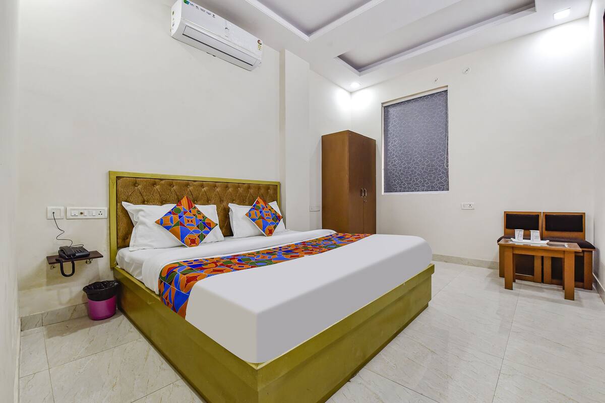 Habitación de hotel ordenada con una cama, un armario, una mesita y una ventana que ofrece una vista decorativa.