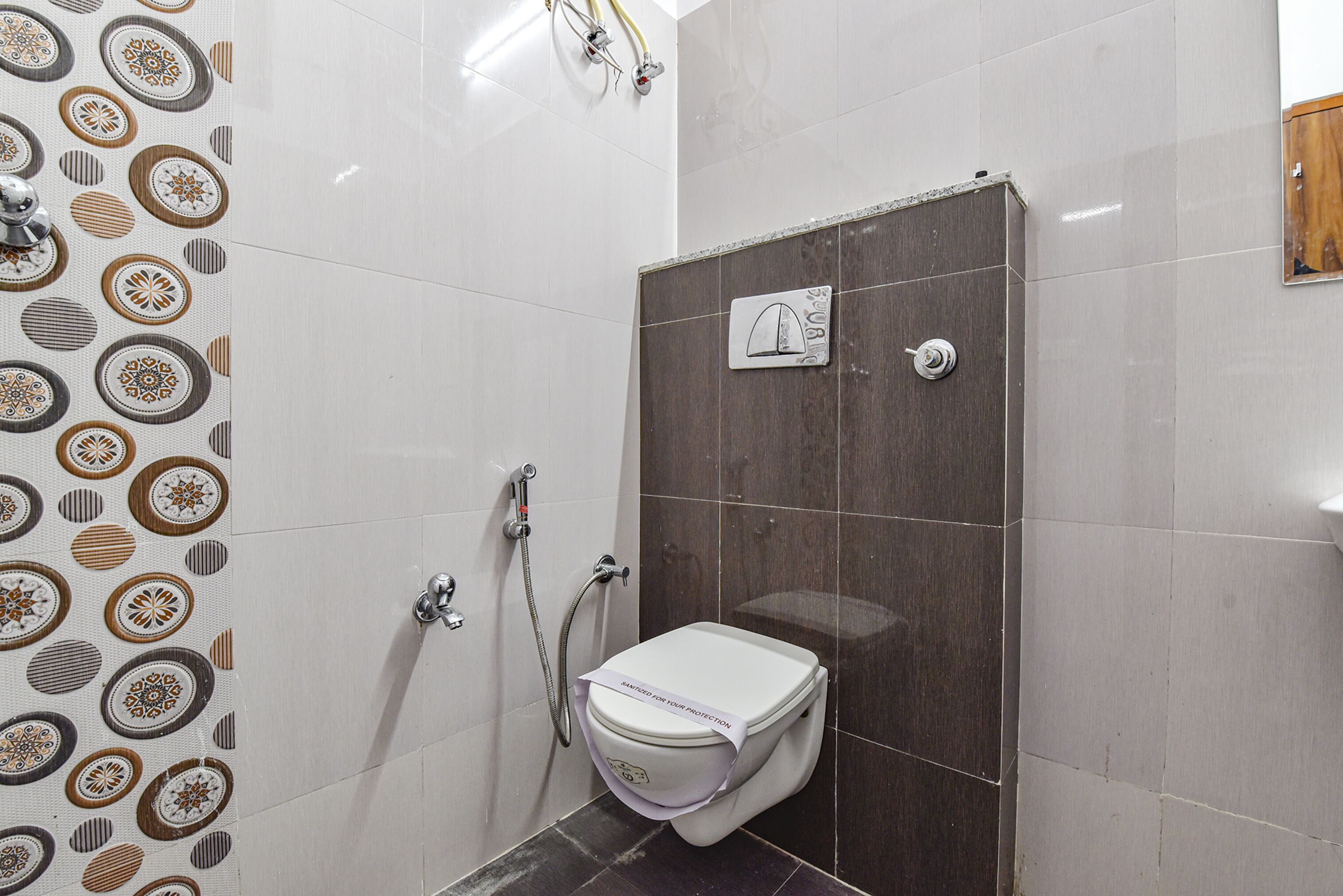 A bathroom with a shower, toilet, and a patterned wall.