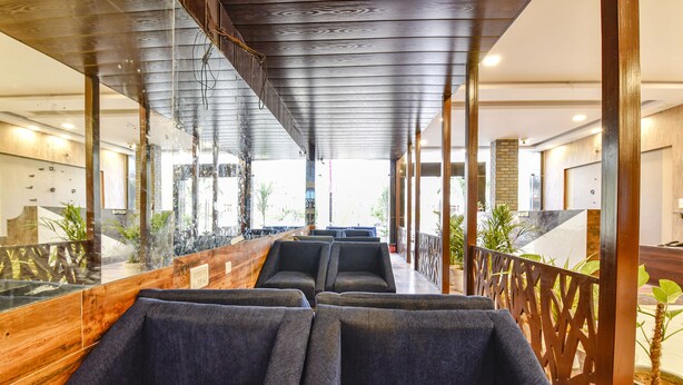 Un moderno vestíbulo de hotel con un mostrador de recepción de madera, zona de estar y grandes ventanales con vistas a la ciudad.