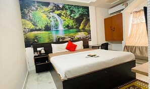 A bedroom with a bed, a nightstand, a red pillow, a wall-mounted TV, and a wooden wardrobe. - Fabhotel Prince (Siliguri)