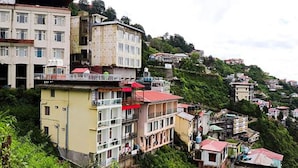 Un quartier résidentiel situé sur une colline, avec des immeubles à plusieurs étages, dont certains sont dotés de balcons et de toits rouges.