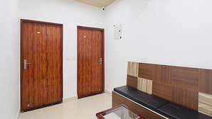 Une pièce avec deux portes en bois, un banc doté d’une tête de lit en bois et une petite table.