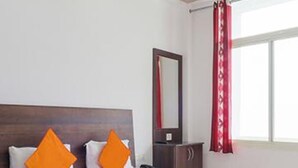 Un lit bien fait, avec une literie blanche et orange, une tête de lit en bois et une table de chevet avec un miroir.