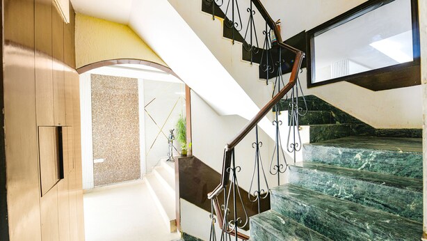 A modern interior with a marble staircase, wooden paneling, and a large mirror reflecting the room. - Fabhotel Mosca (Gurugram)