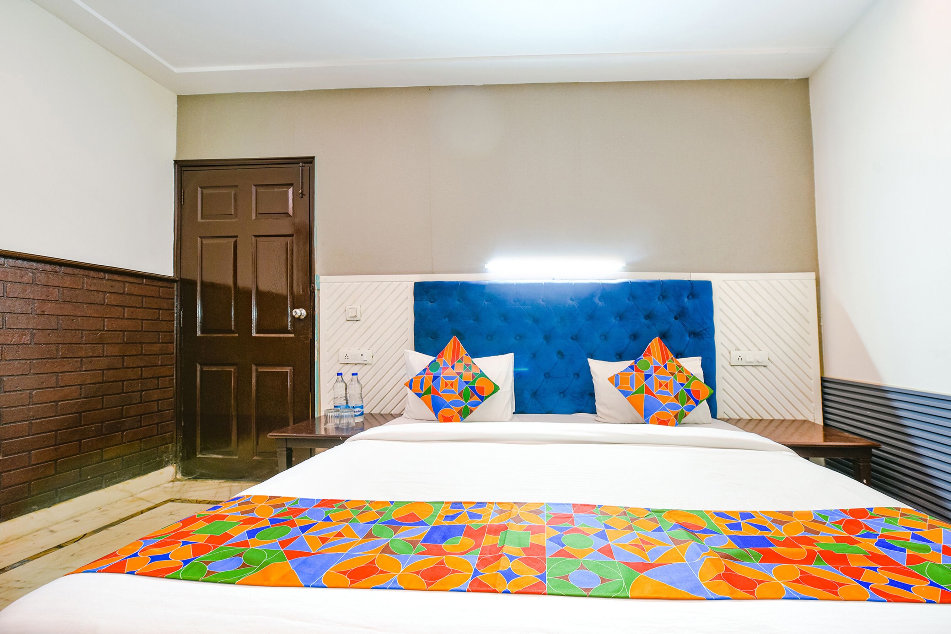 A hotel room with a bed, a headboard, a door, and a nightstand.