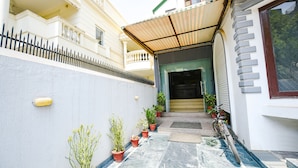 A narrow pathway leading to a building entrance with potted plants and a bicycle. - Fabhotel Mosca (Gurugram)