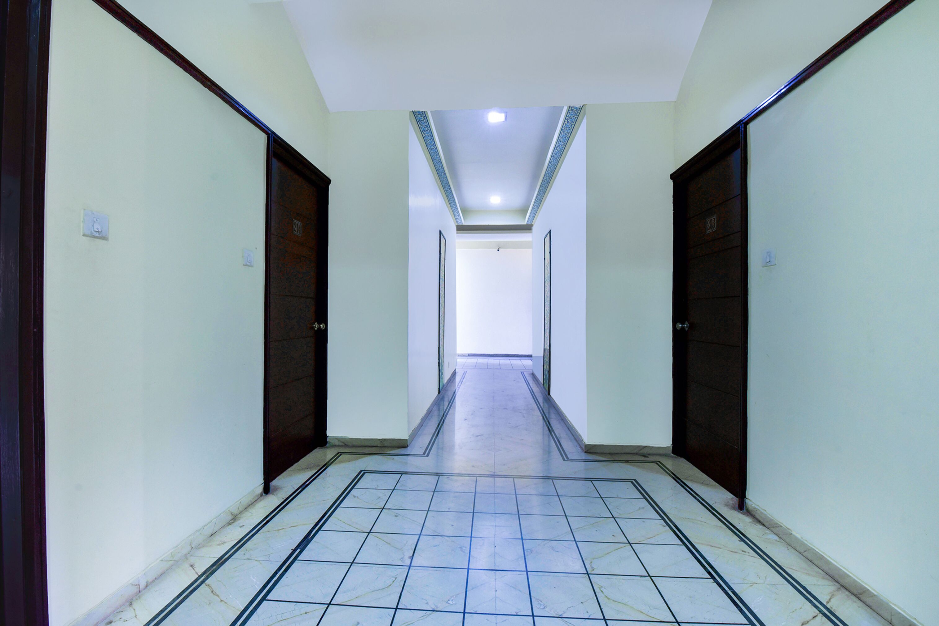 A corridor with tiled flooring, two doors on each side, and a ceiling light.