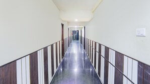A long, narrow hallway with a shiny floor and striped railings on both sides. - Fabexpress Arjun Imperial (Raipur)