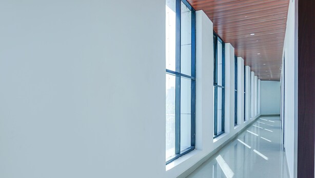 A modern, well-lit hallway with large windows and a polished floor.