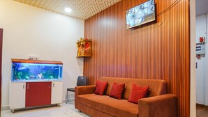A room with a red sofa, a fish tank, and a television mounted on the wall.
