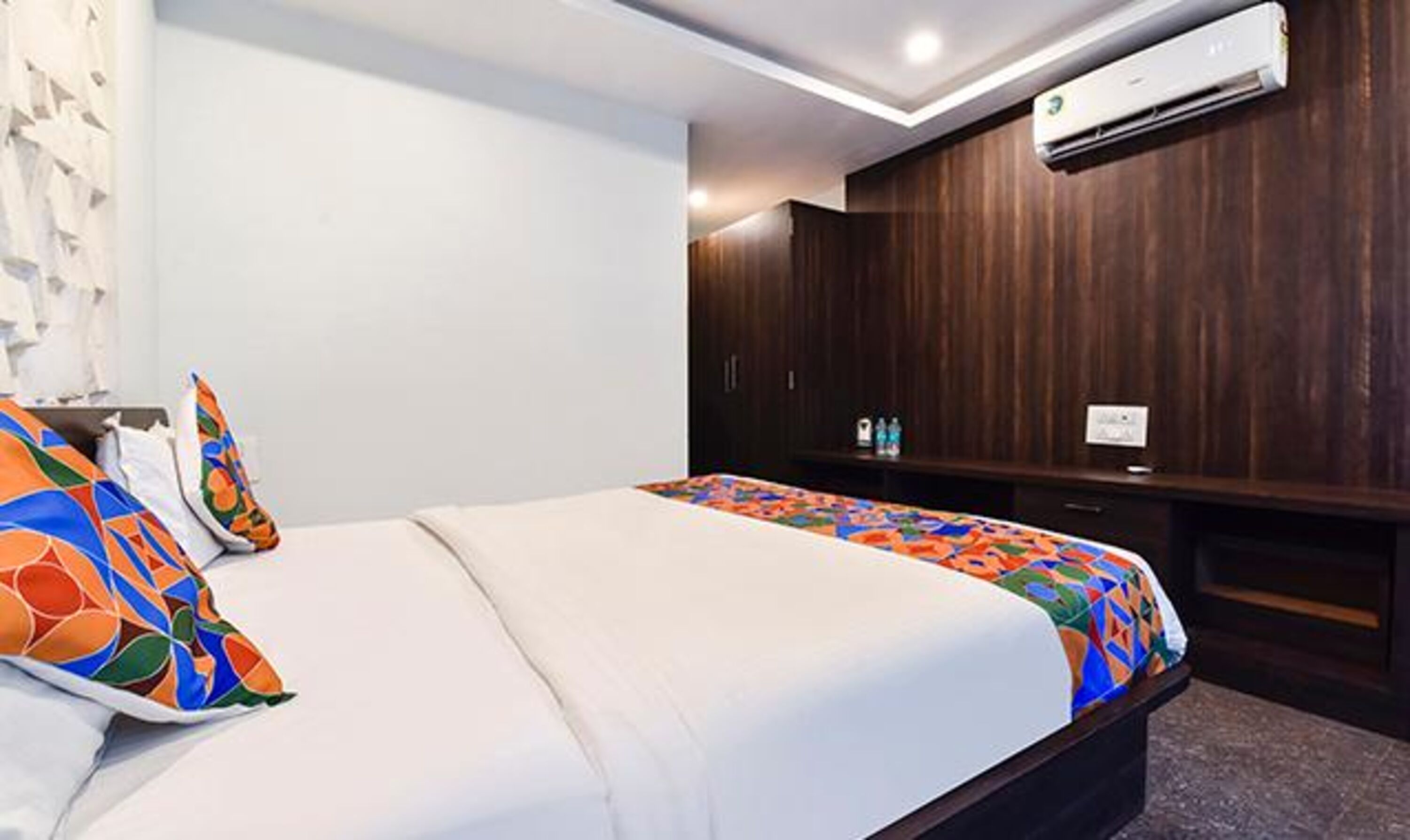 Une chambre d’hôtel avec un lit, une armoire en bois et un appareil de climatisation.