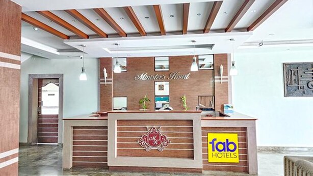 A reception desk with a wooden finish, a logo with a crown, and a sign for 'Fab Hotels'. - Fabhotel Prime Ministers Kourt (Somvarpet)
