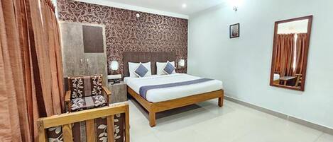 A bedroom with a bed, bedside tables, a chair, a mirror, and a patterned wall.