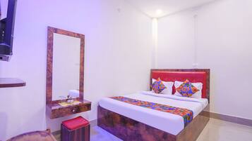 A bedroom with a bed, a mirror, a bedside table, and a red headboard.