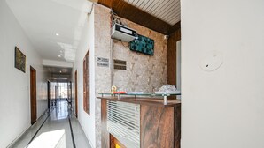 Zona de recepción con un mostrador de vidrio, un televisor montado y un cartel que indica que es una zona libre de humo.