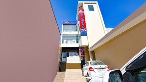 Un hotel llamado FabHotels con una recepción, una escalera y un coche blanco estacionado.