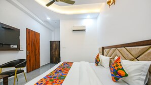 Habitación de hotel con una cama, televisión, puerta de madera y aire acondicionado.