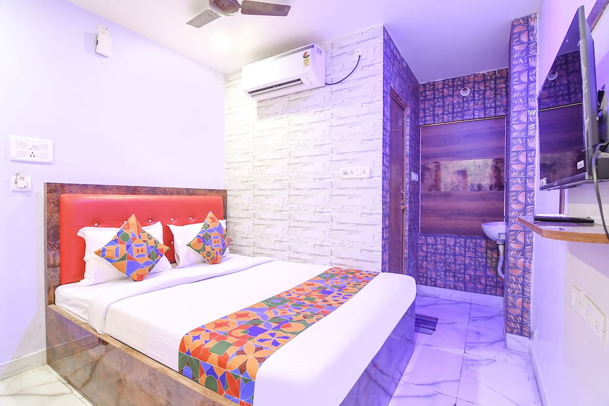 Une chambre d’hôtel avec un lit, une salle de bain avec douche et un téléviseur fixé au mur.
