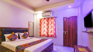 A bedroom with a bed, a wooden door, a television, and an air conditioning unit. - FabHotel Srideep (Kolkata)