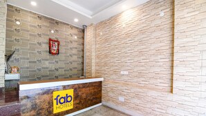A hotel reception area with a modern design, featuring a reception desk with a logo and a patterned wall behind it. - FabHotel Srideep (Kolkata)