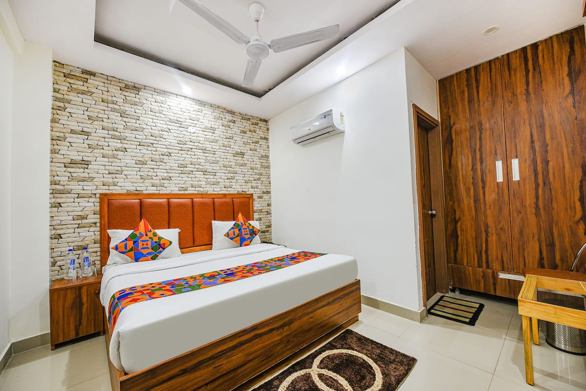 A modern bedroom with a brick-patterned wall, a wooden headboard, and a ceiling fan.