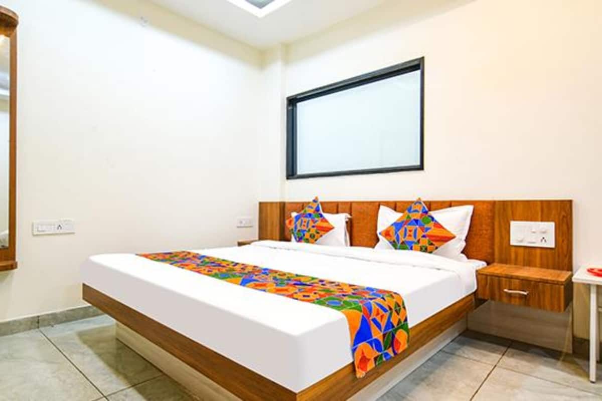 A modern hotel room with a large bed, wooden headboard, and a small bedside table.