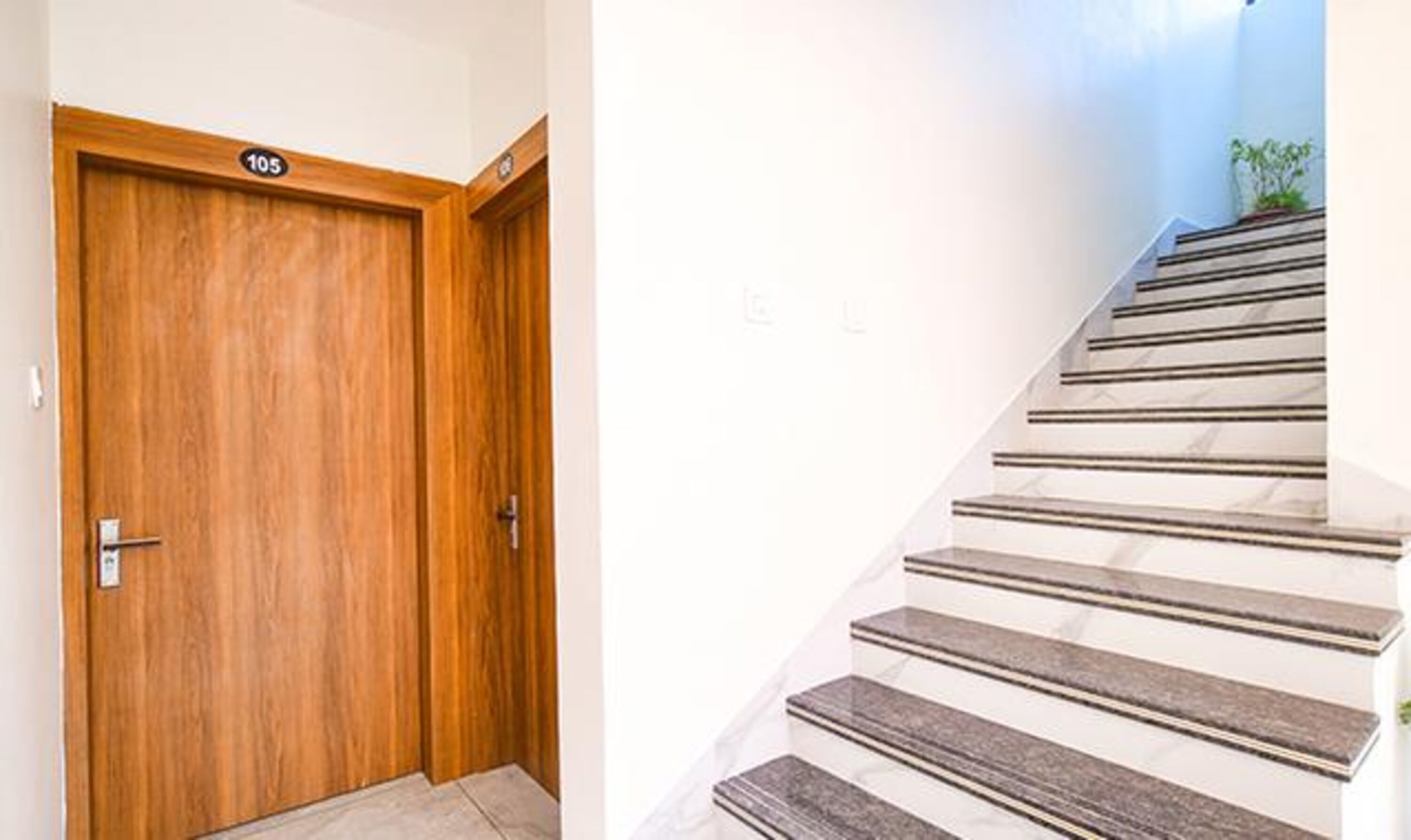 A wooden door with a number plate and a staircase with alternating light and dark steps.
