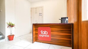 A reception desk with a 'fab express' sign, a potted plant, and a door with a 'NO' sign.