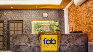 Un mostrador de recepción con un reloj, un cuadro enmarcado y un cartel que dice 'Fab Hotels'.
