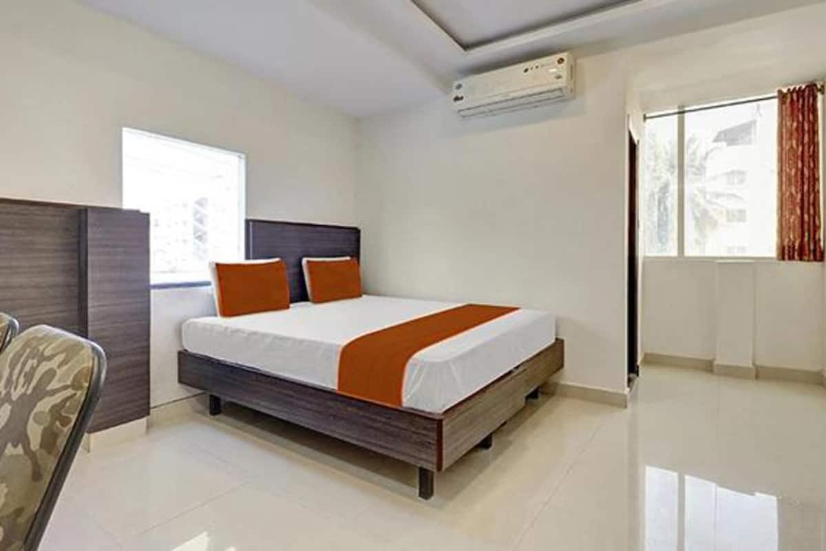 A modern hotel room with a large bed, a headboard, a window with curtains, and an air conditioning unit.