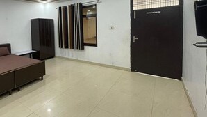 A bedroom with a bed, a wardrobe, a door, and a window with blinds. - Fabhotel Kalawati Palace (Faizabad)
