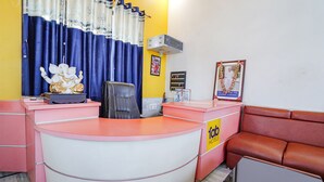 A reception area with a pink desk, a statue of a deity, a framed picture, and a sign for 'Fabi Hotels'. - FabExpress Savitri Resort (Sohawal)