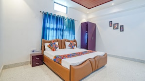A modern bedroom with a bed, curtains, a wardrobe, and a small bedside table. - FabExpress Savitri Resort (Sohawal)