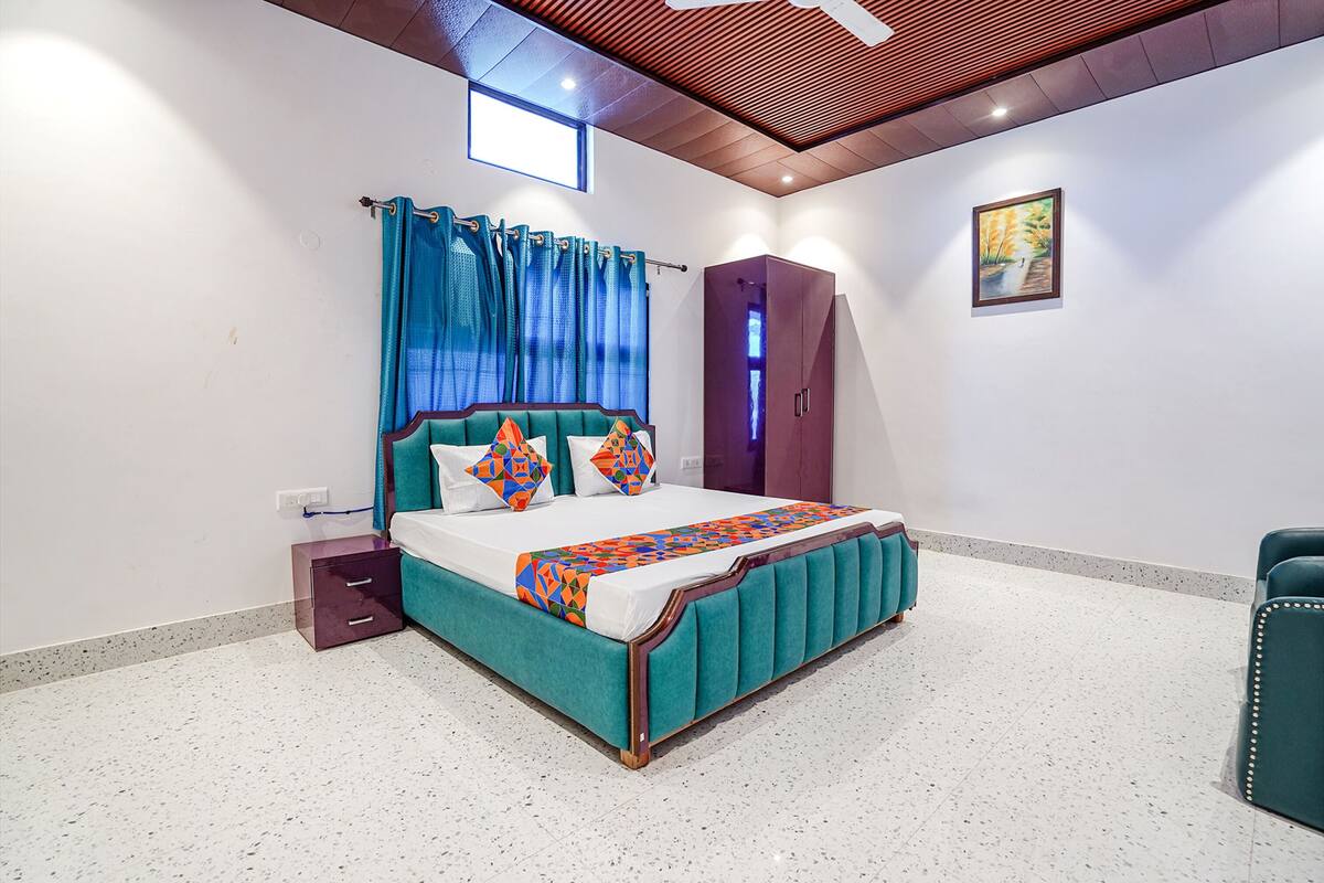 A bedroom with a bed, a wardrobe, a nightstand, and a painting on the wall.
